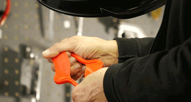 Hands holding an orange rubber part